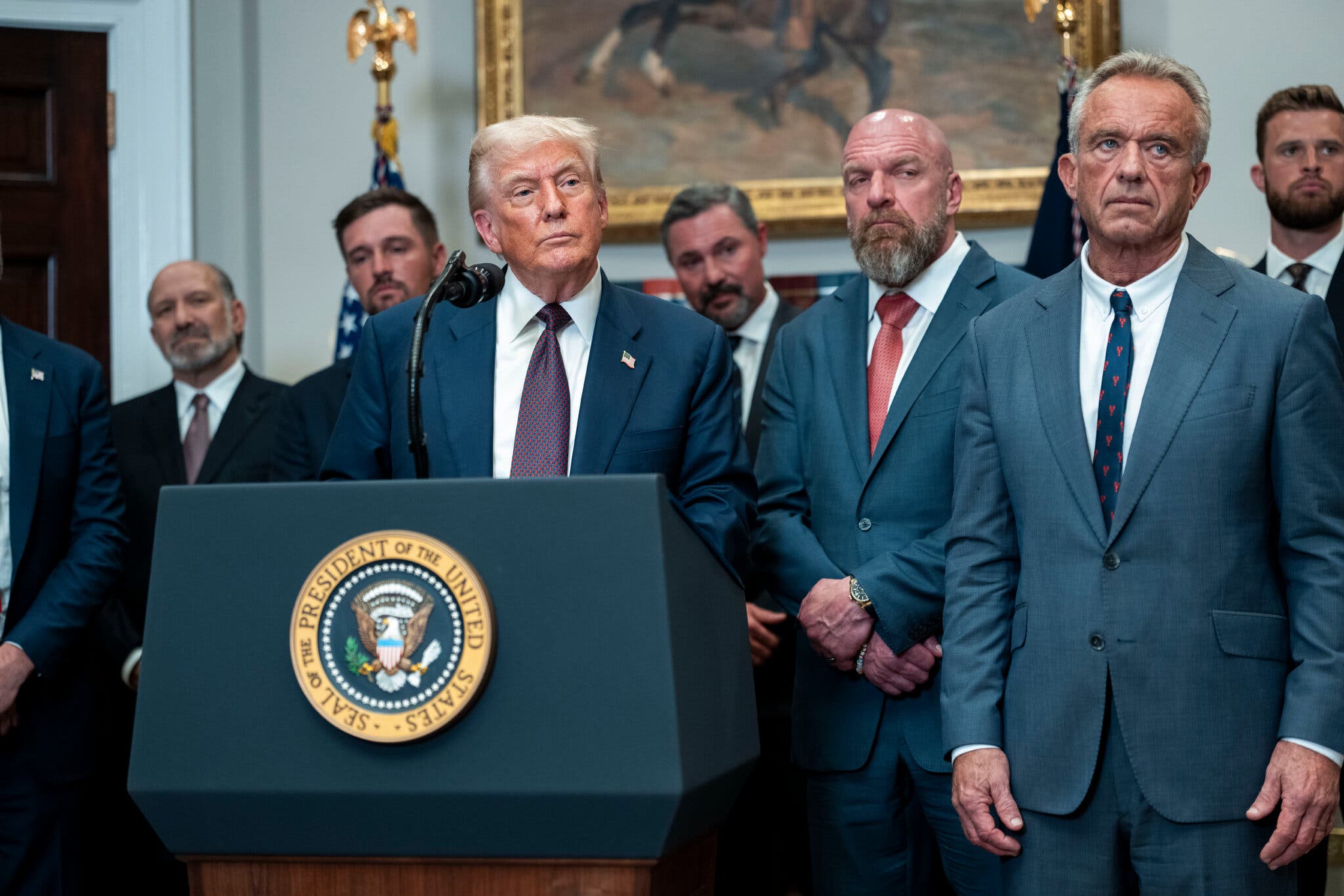 President Trump signs executive order reviving the Presidential Fitness Test, surrounded by athletes and officials.